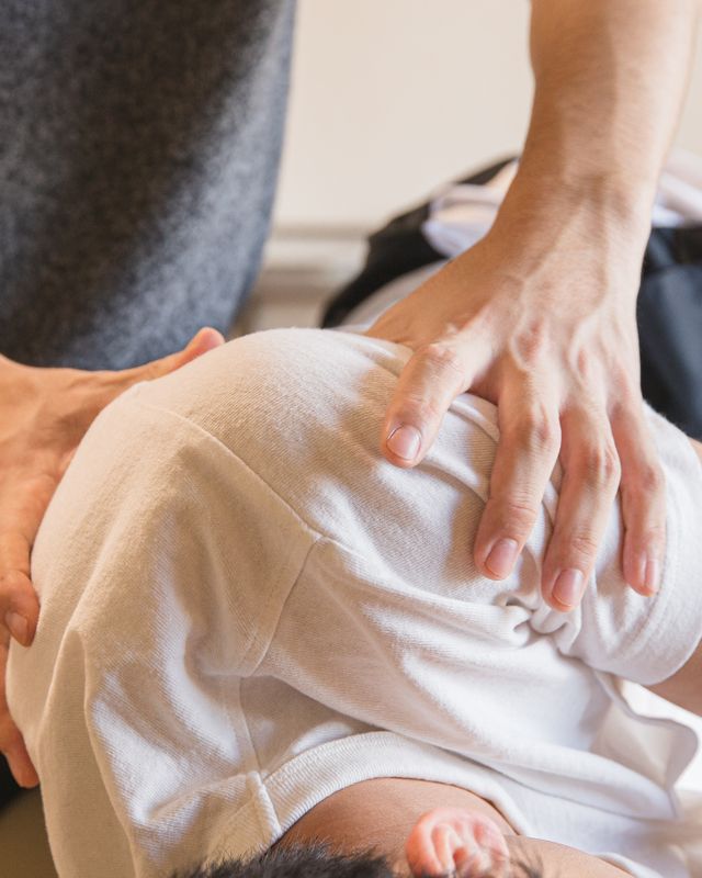 Massagetherapeut die de schouder van een cliënt behandelt